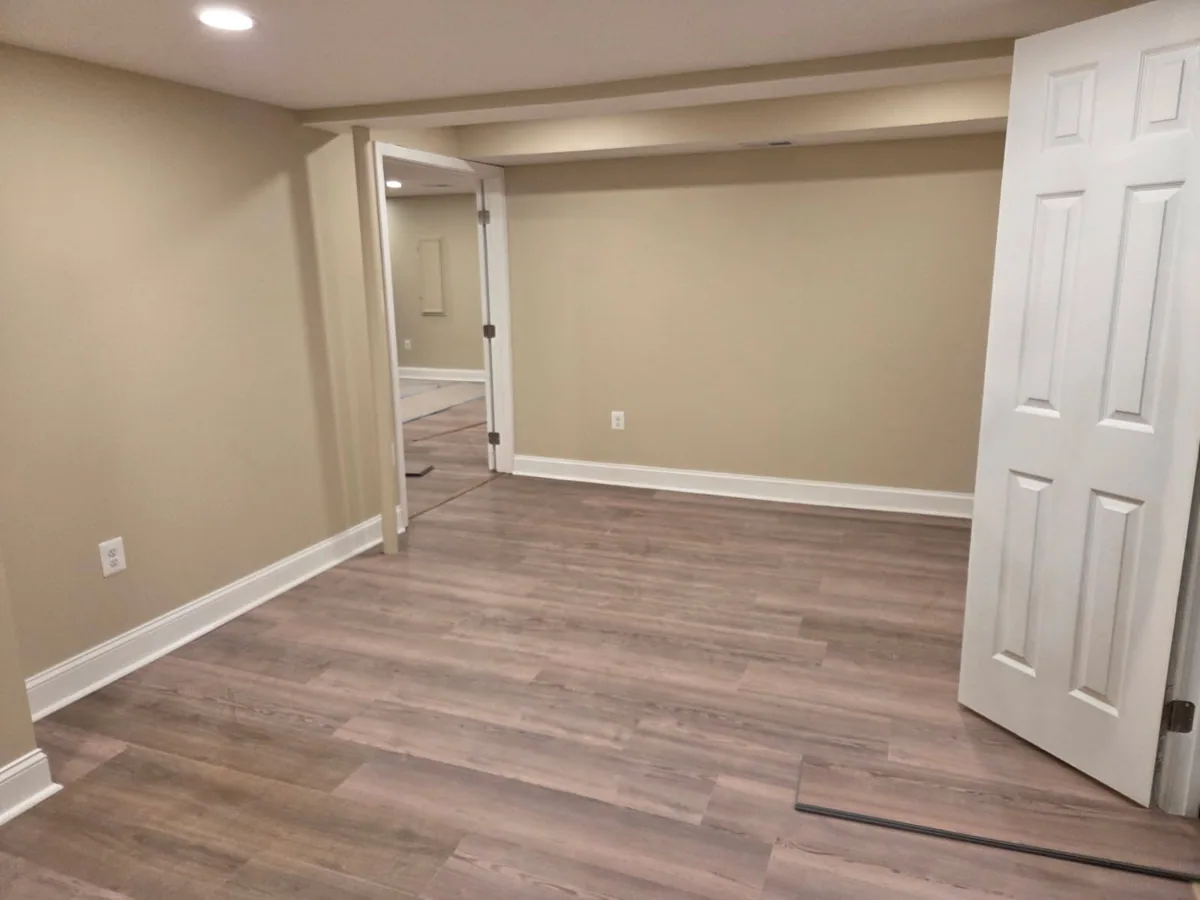 Finished basement remodeled by All Phases NOVA with plank flooring, recessed lighting, and white trim