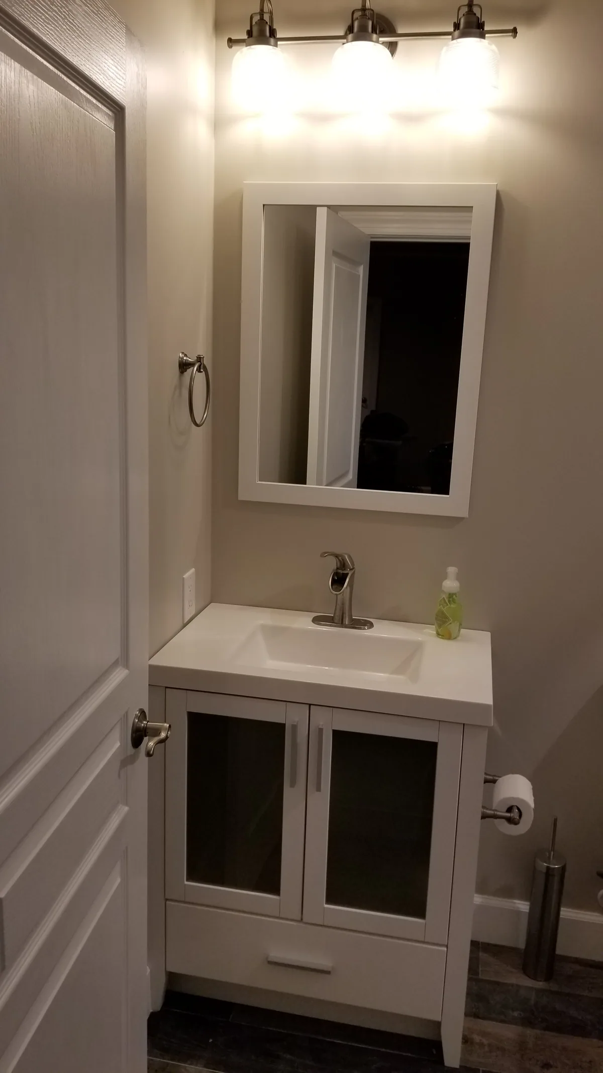 Finished bathroom vanity with white cabinetry, framed mirror, and brushed nickel fixtures