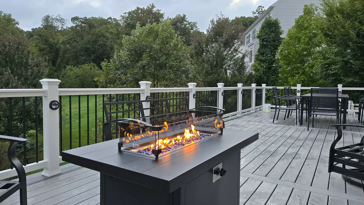 Finished composite deck with white and black railings and an outdoor fire table