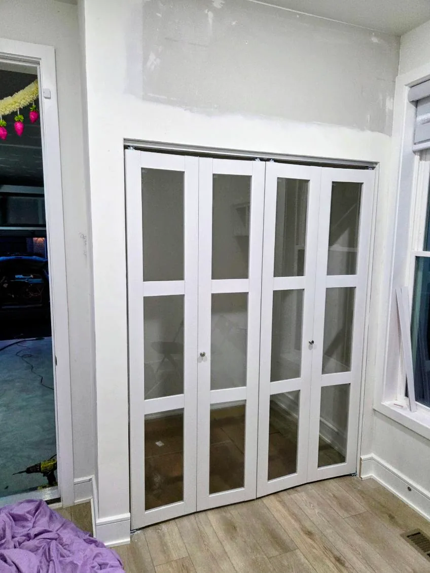 Glass-paneled white folding doors during an interior installation